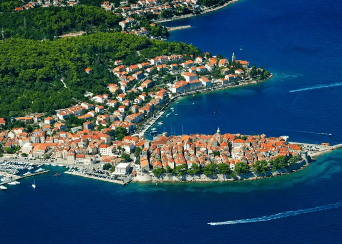 An island with buildings and trees in the water, offering stunning views of Korčula in the background, perfect for day trips or private boat tours from Dubrovnik.