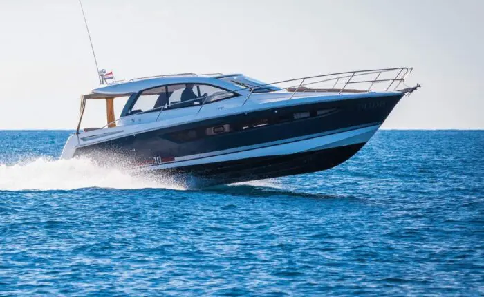 A motor yacht speeds across a calm blue sea with a white wake behind it, under a clear sky—a perfect setting for one of Dubrovnik's private boat tours.