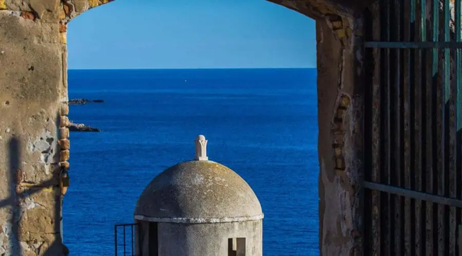 The stone archway with the "Anno 1634" inscription overlooks a turret and the blue ocean on a sunny day. Perfect for day trips in Dubrovnik, consider private boat tours to explore more stunning sights like this along the coast.