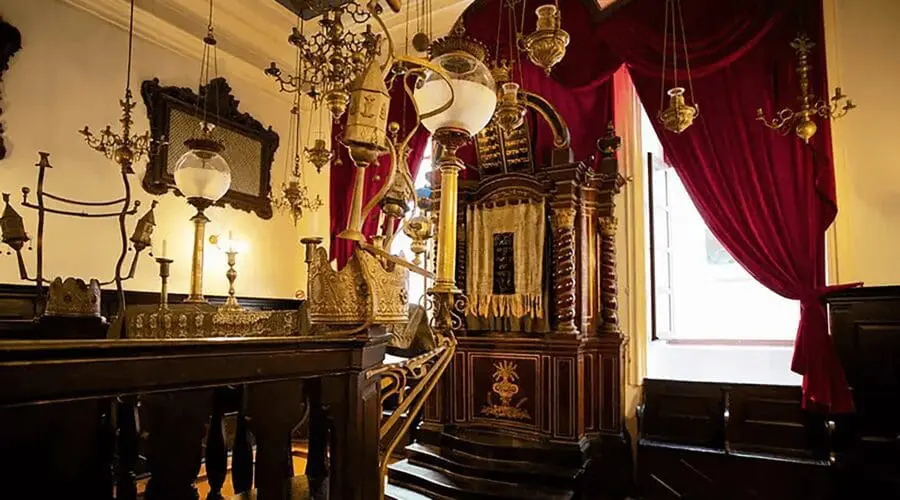 A richly decorated room with ornate gold fixtures, chandeliers, red velvet drapes, and intricate wooden furniture, including a raised pulpit area—perfect for those luxury day trips or private boat tours departing from Dubrovnik.