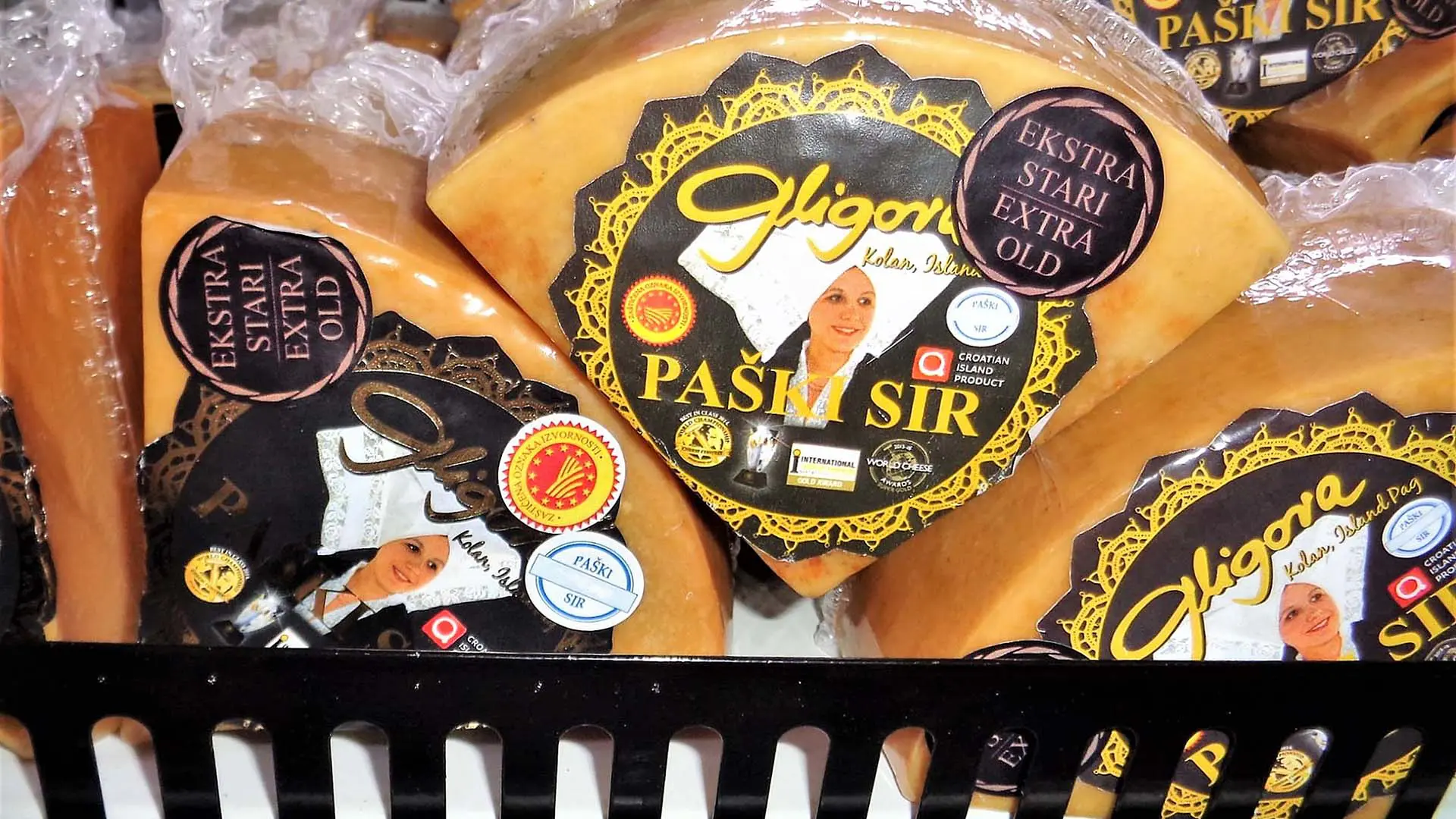 Close-up of packaged cheese labeled "Gligora Paški Sir Ekstra Stari Ekstra Old" in a display, perfect for sampling authentic Dalmatian flavors on your travels.