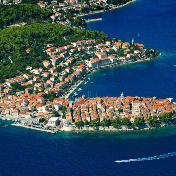 An island with buildings and trees in the water, offering stunning views of Korčula in the background, perfect for day trips or private boat tours from Dubrovnik.