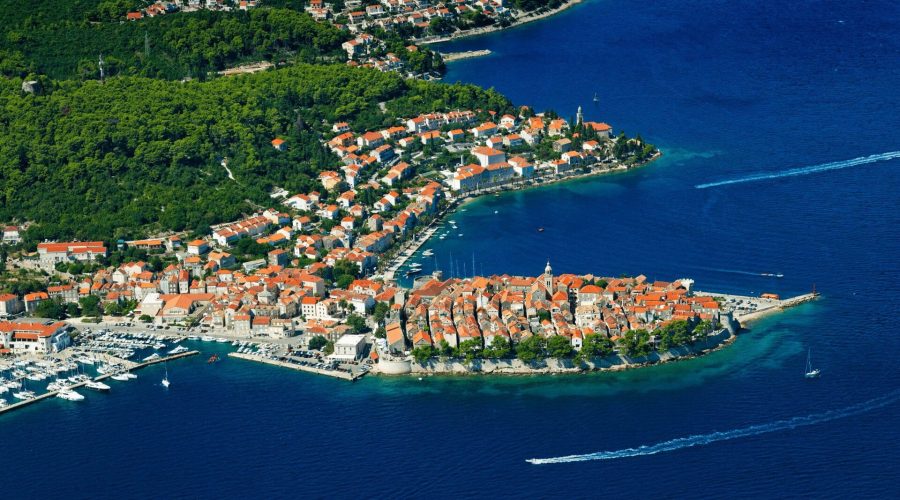 An island with buildings and trees in the water, offering stunning views of Korčula in the background, perfect for day trips or private boat tours from Dubrovnik.