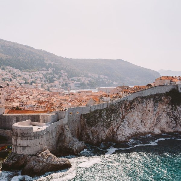 Panoramic view of Dubrovnik, Croatia, showcasing its historic walled city by the Adriatic Sea, with surrounding hills and clear skies in the background—perfect for private boat tours or day trips.