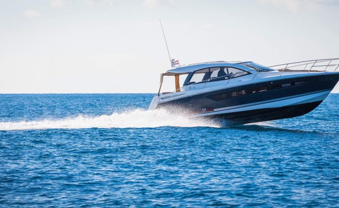 A motor yacht speeds across a calm blue sea with a white wake behind it, under a clear sky—a perfect setting for one of Dubrovnik's private boat tours.