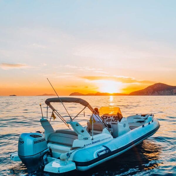A motorized inflatable boat floats on calm waters during sunset, with silhouetted hills in the background under a partially cloudy sky, perfect for private boat tours and serene day trips in Dubrovnik.