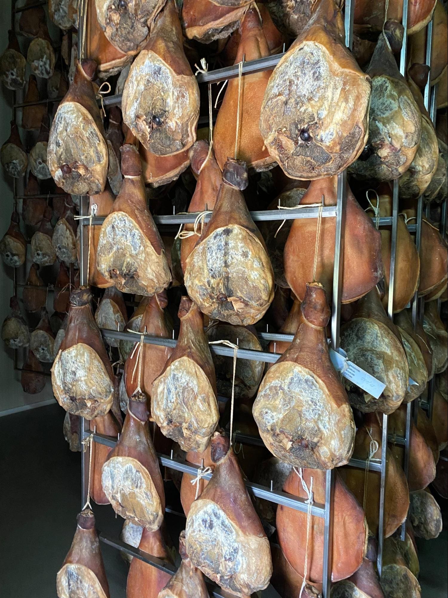 In a cozy corner of Dalmatia, several cured ham legs hang on metal racks in a storage room, ready to inspire local dishes.