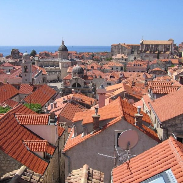 View over Dubrovnik, a historic coastal city with red-tiled rooftops, stone buildings, and domed churches set against the blue sea—perfect for exploring June events and discovering unique things to do.