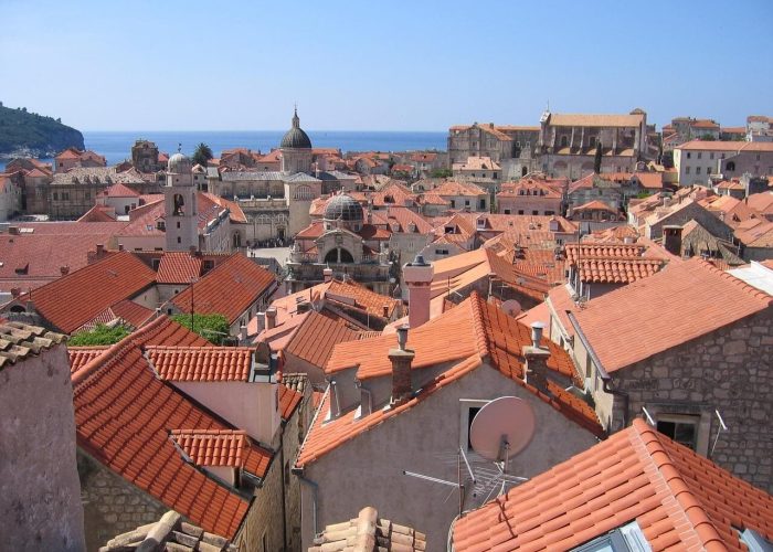 View over Dubrovnik, a historic coastal city with red-tiled rooftops, stone buildings, and domed churches set against the blue sea—perfect for exploring June events and discovering unique things to do.