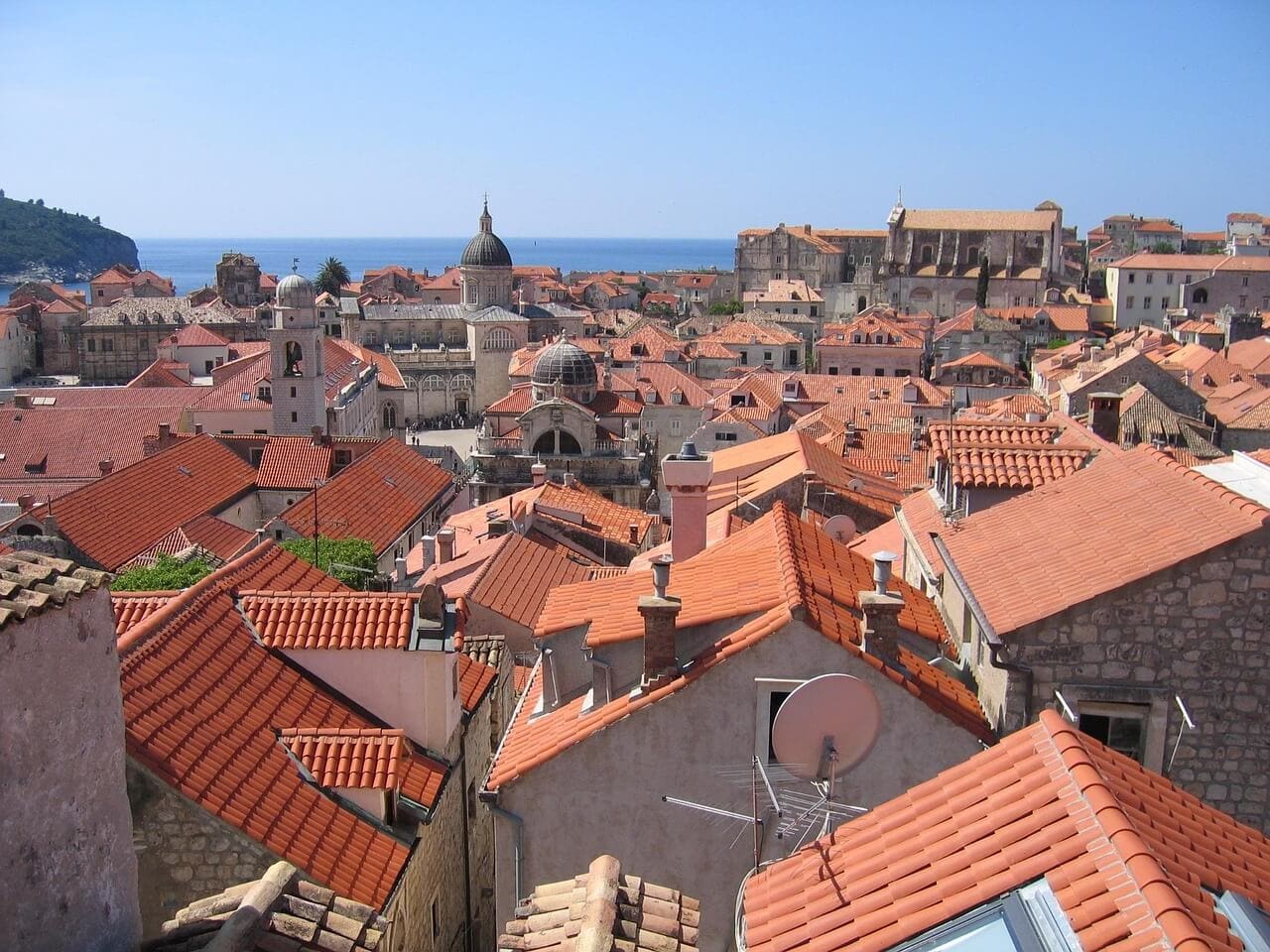 View over Dubrovnik, a historic coastal city with red-tiled rooftops, stone buildings, and domed churches set against the blue sea—perfect for exploring June events and discovering unique things to do.